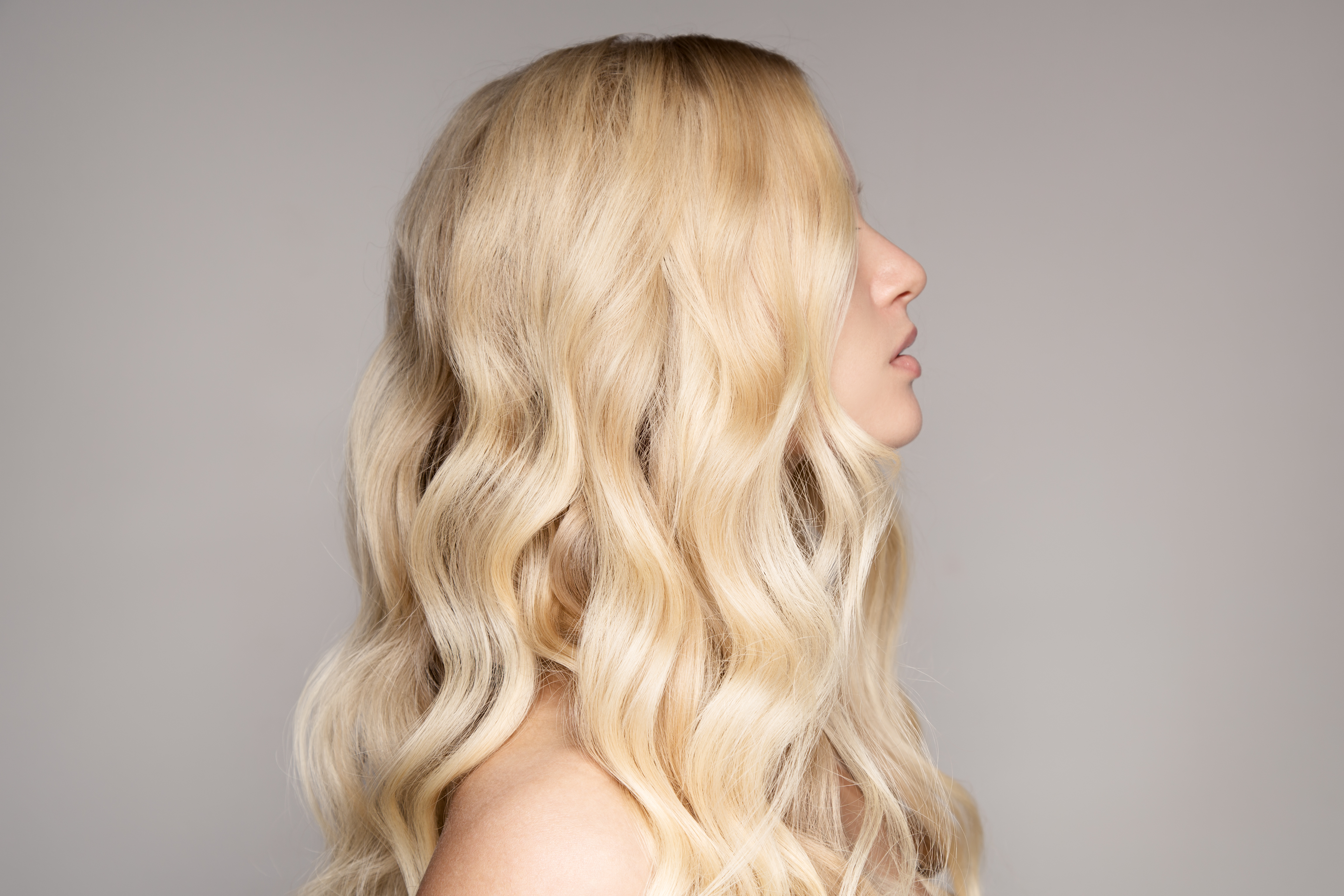 Side profile of a model with long, wavy blonde hair